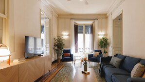 Ein Wohnzimmer mit Fernseher, Sofa, Sesseln und Couchtisch.