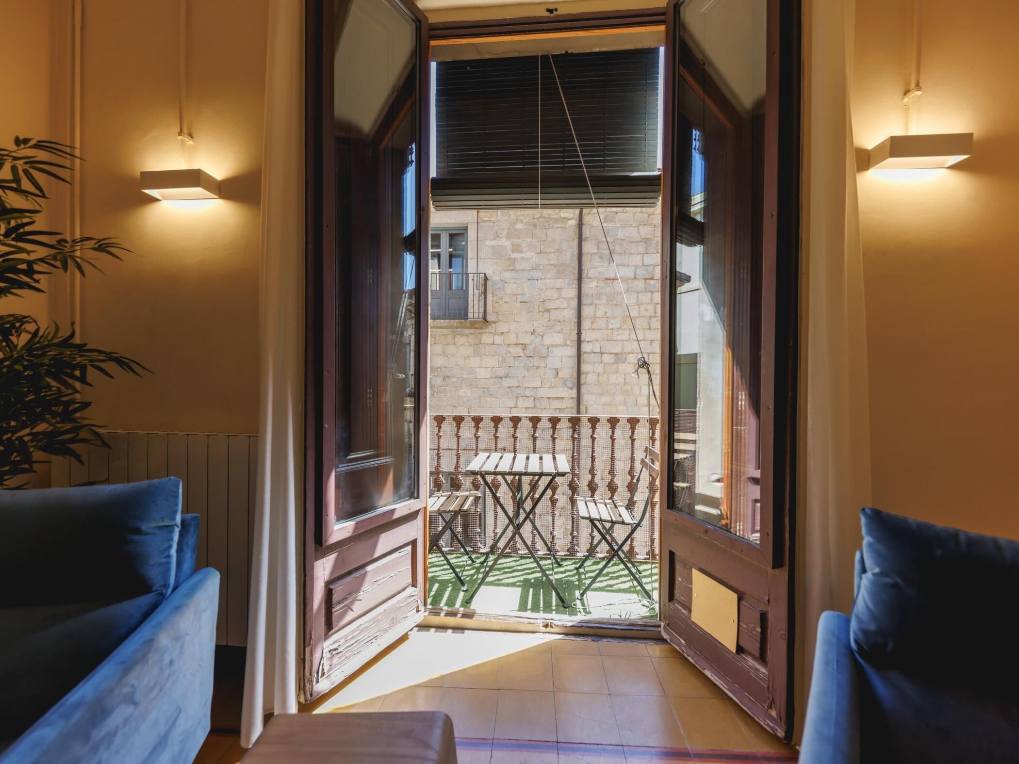 A room with a wooden door leading to a balcony with a table and chairs.