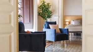Ein Hotelzimmer mit einem Bett, einem Schreibtisch, einem Sessel und einem Blumentopf, mit einem gemusterten Boden.