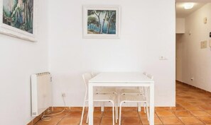 Ein Zimmer mit einem weißen Tisch, Stühlen, einem Heizkörper und zwei gerahmten Bildern an der Wand.