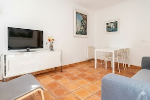 A living room with a TV, white furniture, a dining table with chairs, and artwork on the walls. - Central, Spacious and Bright Apartment, Palma 4 (Palma)