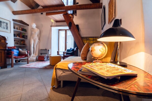 A cozy room with a bed, a desk with a lamp, a globe, and a bookshelf.