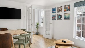 Una stanza con un tavolo da pranzo, sedie, una televisione, una porta e opere d'arte alle pareti.