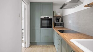 Una cucina compatta con forno a microonde, forno e piano di lavoro in legno.