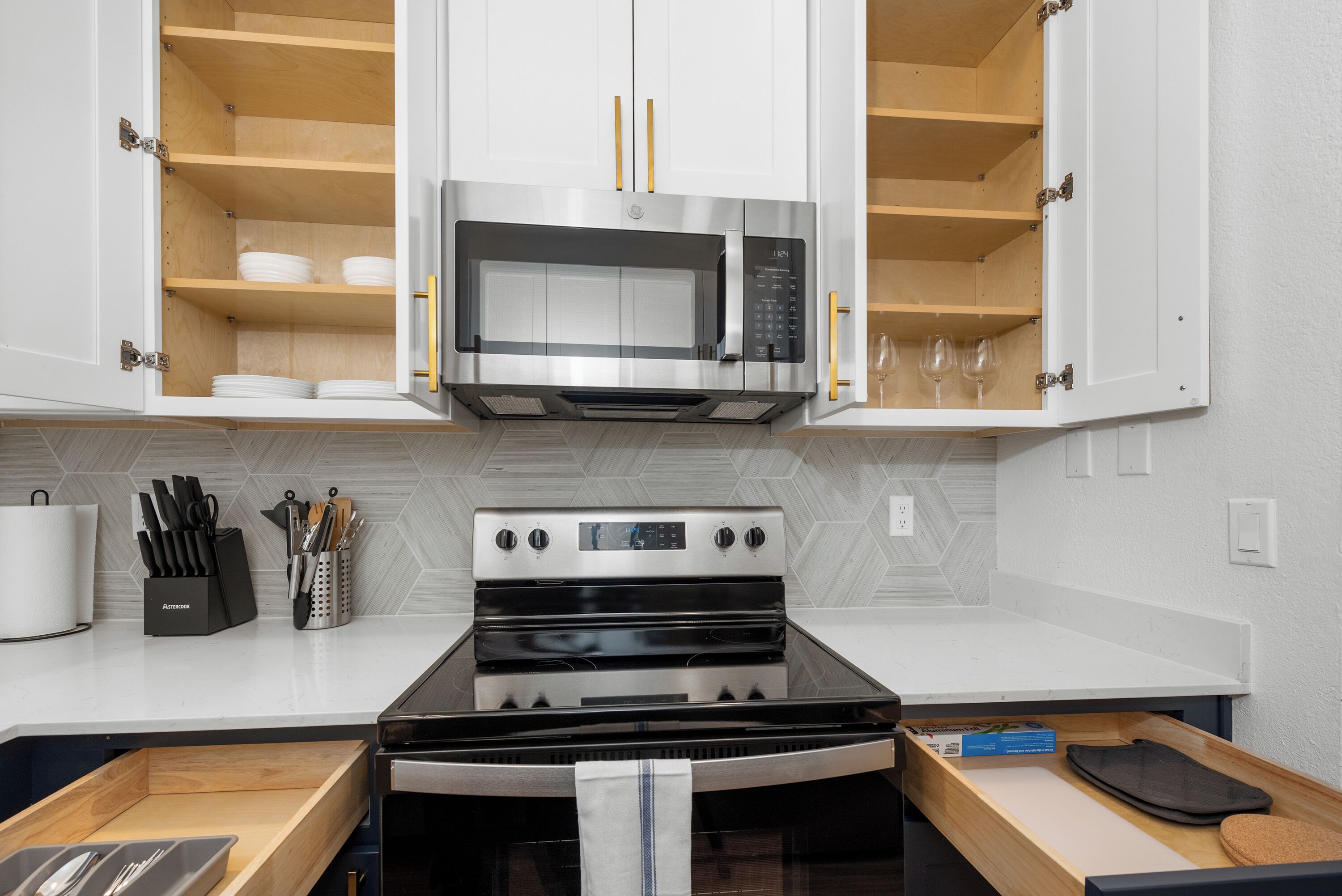 A kitchen with a microwave, oven, and wooden cabinets.