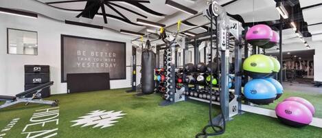 A gym with a motivational quote, weightlifting equipment, and exercise balls.