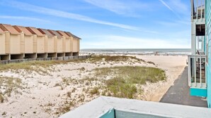 Blick auf einen Strand mit einem Gebäude mit mehreren Balkonen.