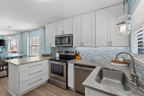 A modern kitchen with white cabinets, a stainless steel range, and a built-in microwave. - Beachfront Condo with Pool & Porch Swing (Gulf Shores)