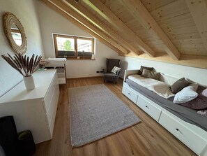 Ein gemütliches Schlafzimmer im Dachgeschoss mit einem Hochbett, einem Schreibtisch und einem Fenster mit Blick auf eine Brücke.