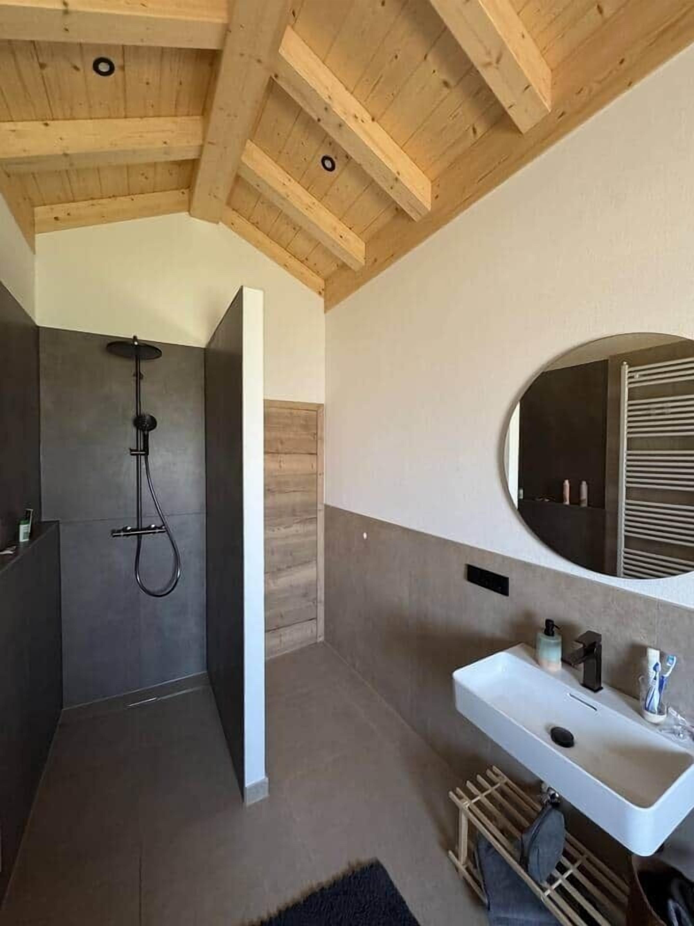 Ein modernes Badezimmer mit Dusche, Waschbecken und Spiegel.