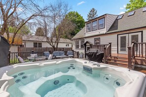 Patio con jacuzzi, una parrilla cubierta y una terraza de madera.
