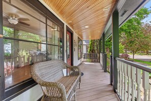 A covered porch with a wicker bench, large windows, and a view of the outdoors. - Lake City Hideaway (Coeur d'Alene)