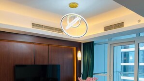 A modern living room with a flat-screen TV, a round coffee table, and a sofa with cushions. - Luxury hotel apartment with a charming view of the Nile and the pyramids Hilton (Cairo Governorate)