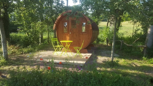 A wooden cabin with a small patio area, a table, and two chairs.