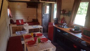 Cozinha compacta com área de refeições, paredes de madeira e uma janela.