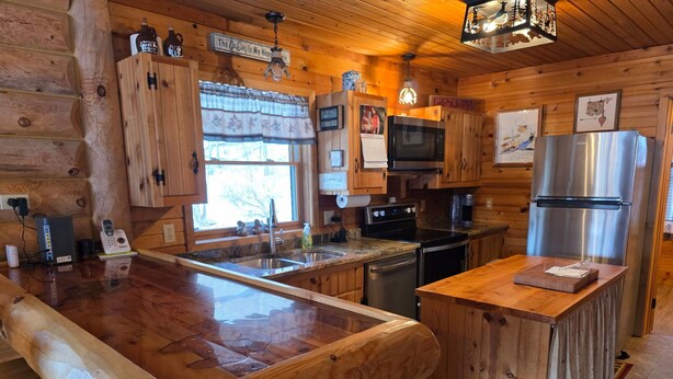 A wooden cabin-style kitchen with a central island, built-in appliances, and a window with a view.