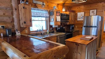 A wooden cabin-style kitchen with a central island, built-in appliances, and a window with a view.