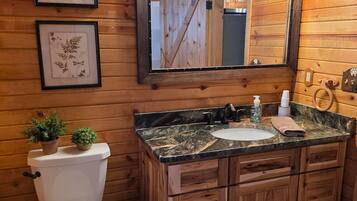 A wooden cabin bathroom with a toilet, sink, and vanity.