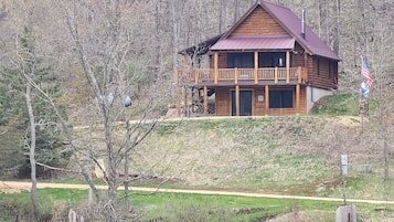 A wooden cabin with a balcony, a chimney, and a flag.