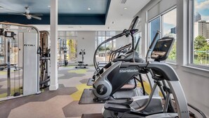 Academia com esteiras, aparelhos de musculação e ventilador de teto.