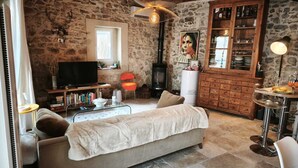 Een gezellige woonkamer met een stenen muur, een open haard, een televisie en een eethoek met een tafel en stoelen.
