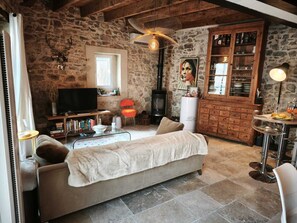 A cozy living room with a stone wall, a fireplace, a television, and a dining area with a table and chairs. - Magnificent house in Provence at the foot of the Château de Boulbon (Boulbon)