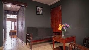 Ein Zimmer mit einer Couch, einem Tisch mit einer Vase, einer Holztür und einem gerahmten Bild an der Wand.
