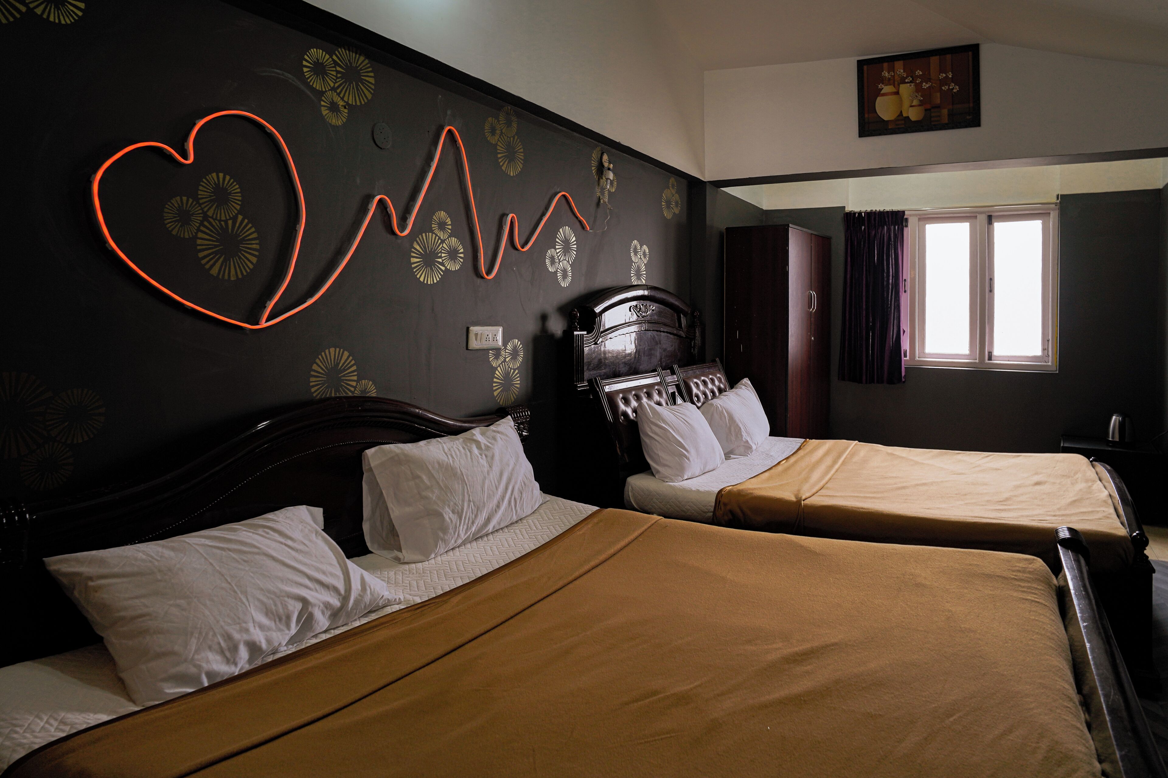 Two single beds with headboards, a wall with a heart-shaped light fixture, and a window with curtains.