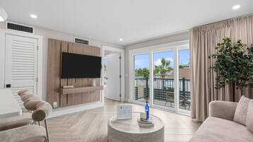A modern living room with a flat-screen TV, a round coffee table, and a sofa.