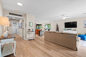 A spacious living area with a large sofa, a television, and a dining area with a table and chairs. - Salty Clover𓇼Vintage Vibes + Modern Comfort (Oak Island)