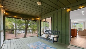 A covered porch with a wooden bench, a patterned rug, and a view of the outdoors. - Salty Clover𓇼Vintage Vibes + Modern Comfort (Oak Island)