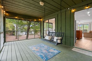 A covered porch with a wooden bench, a patterned rug, and a view of the outdoors. - Salty Clover𓇼Vintage Vibes + Modern Comfort (Oak Island)
