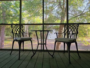 A covered outdoor area with two chairs and a small table, surrounded by a metal railing. - Salty Clover𓇼Vintage Vibes + Modern Comfort (Oak Island)