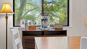 A kitchen with a coffee maker, blender, and radio on a wooden counter by a window with a view of trees. - Salty Clover𓇼Vintage Vibes + Modern Comfort (Oak Island)