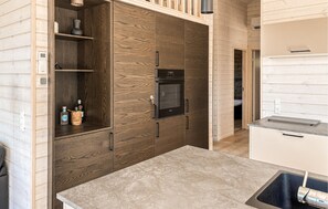 A modern kitchen with wooden cabinetry, a built-in oven, and a countertop with a sink. - 3 bedroom beautiful home in Fjerritslev (Fjerritslev)