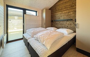 A bedroom with a bed, a sliding door, and a wooden wall. - 3 bedroom beautiful home in Fjerritslev (Fjerritslev)