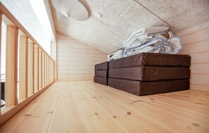 Une pièce dotée d’un plancher en bois, d’un banc intégré avec espace de rangement, d’un ventilateur de plafond et offrant une vue sur l’extérieur.