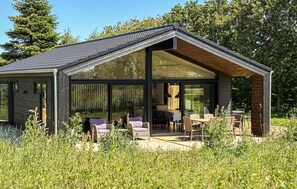 A modern house with large glass windows, a dining area with outdoor seating, and a garden setting. - 3 bedroom beautiful home in Fjerritslev (Fjerritslev)