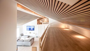 A modern interior with a sloped ceiling, a sofa, a TV, and a wooden floor. - Gorgeous home in Sæby with sauna (Sæby)
