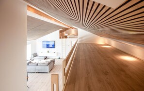 A modern interior with a sloped ceiling, a sofa, a TV, and a wooden floor. - Gorgeous home in Sæby with sauna (Sæby)