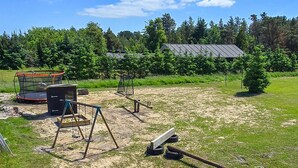 A grassy outdoor area with a trampoline, swings, and a seesaw. - Gorgeous home in Sæby with sauna (Sæby)