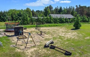 A grassy outdoor area with a trampoline, swings, and a seesaw. - Gorgeous home in Sæby with sauna (Sæby)