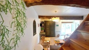 A staircase leading to a living area with a wooden ceiling, a hanging light fixture, and a view of a kitchen area.
