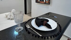 Eine moderne Küche mit schwarzem Arbeitsplatten, einer Glas-Schüssel, einer Gabel, einem Servietten und einem Teller mit einer schwarzen Serviete. Es gibt einen Deckenventilator, eingelassene Beleuchtung und gerahmte Bilder an der Wand.