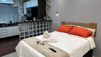 Een moderne hotelkamer met een groot bed, een ingebouwde televisie, een kitchenette en een badkamer.
