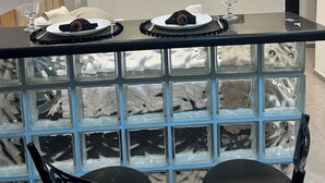 Ein moderner Essbereich mit einem Glastisch, schwarzen Stühlen und einem Deckenventilator.