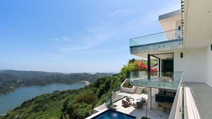 Ein modernes Haus mit einem Glasbalkon mit Blick auf einen See und Grünflächen.