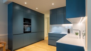 A modern kitchen with dark blue cabinets, a white countertop, and a built-in oven. - FLH Heart of Rossio Flat I (Lisboa ciudad)