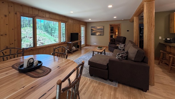 A wooden interior with a dining table, chairs, a sofa, and a TV. - Charming 3-bedroom cabin in Woodruff perfect for relaxing getaways (Woodruff)