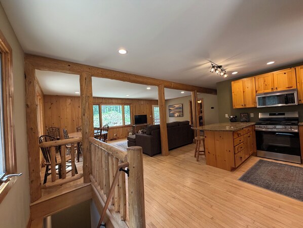 A spacious kitchen with wooden cabinets, a large island, and a dining area with a wooden railing.